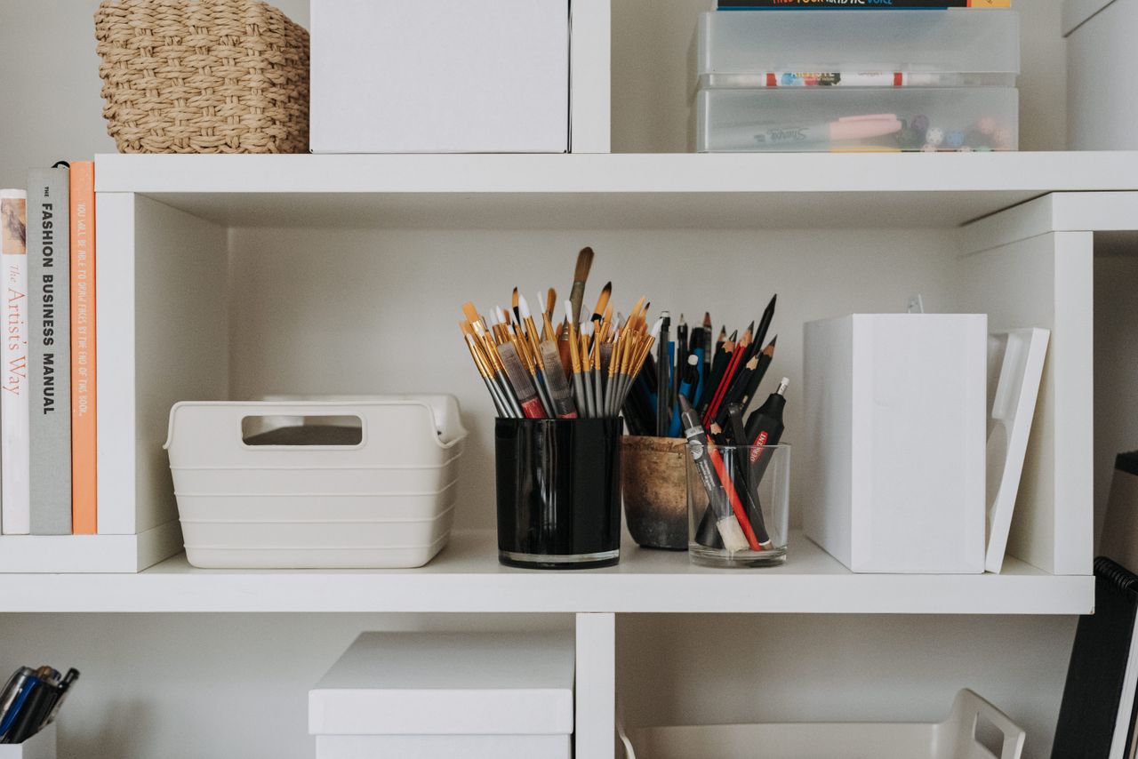 collection-03 Collection of paintbrushes and pencils placed on white shelf with containers and equipment for painting in modern light art studio