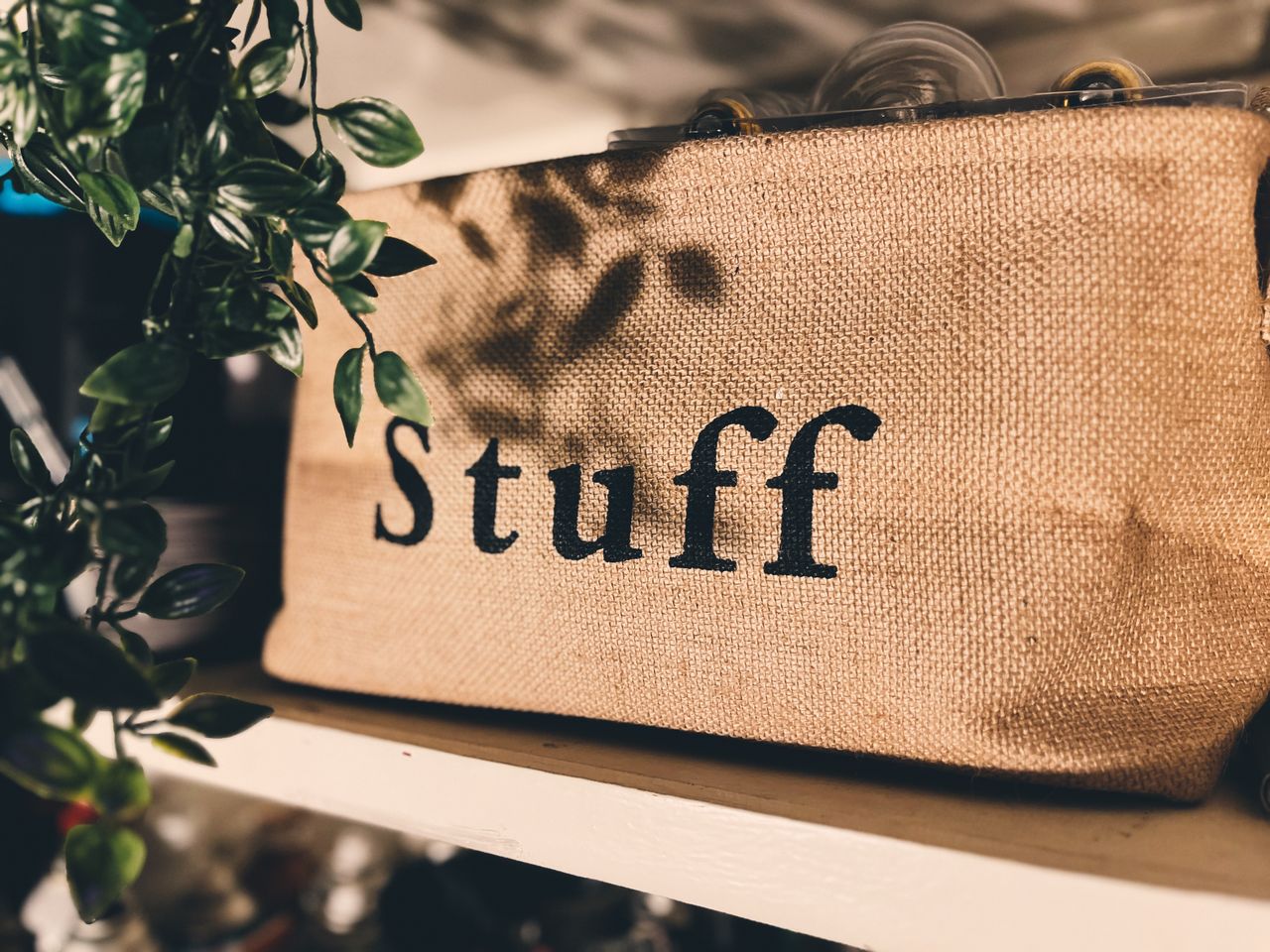 faq-img Close-up of a burlap bag labeled Stuff on a wooden shelf with plants.